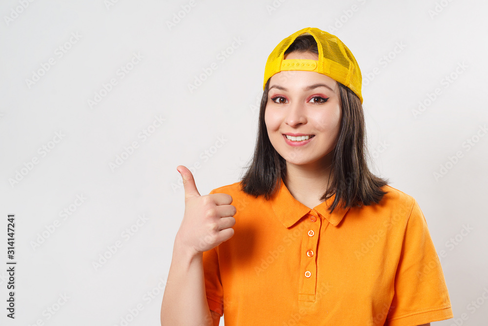 a girl woman in a bright Polo shirt shows a thumbs up gesture and smiles a girl woman in a bright Polo shirt shows a thumbs up gesture and smiles