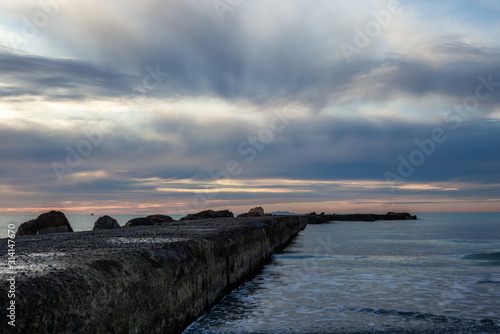 A pier on the Mediterranean Sea in Tuscany at sunset with an island in the background