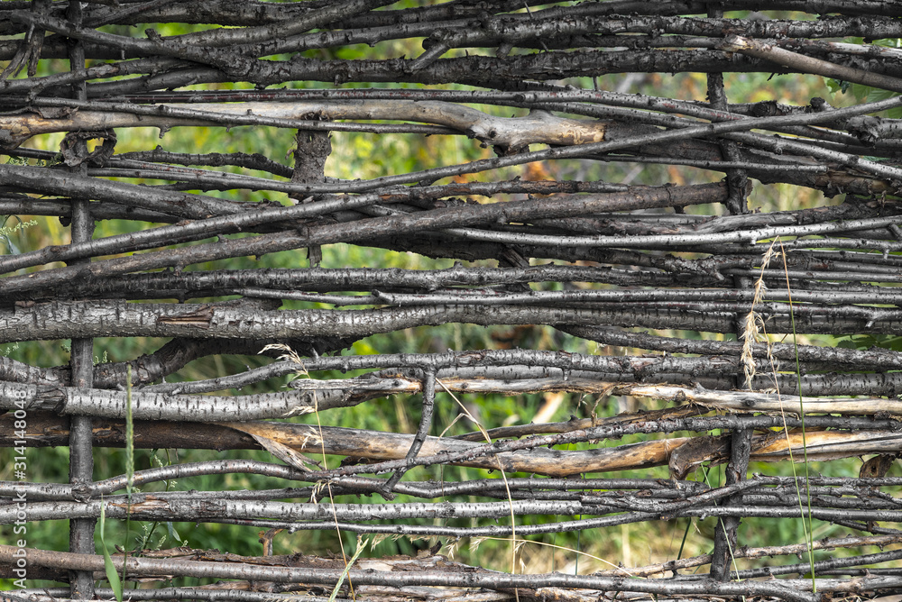 Wooden fence made of interwoven thin tree branches