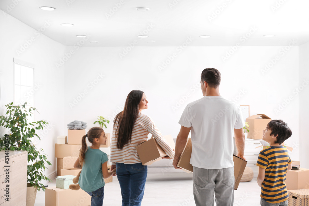 Family in room with cardboard boxes on moving day Family in room with cardboard boxes on moving day