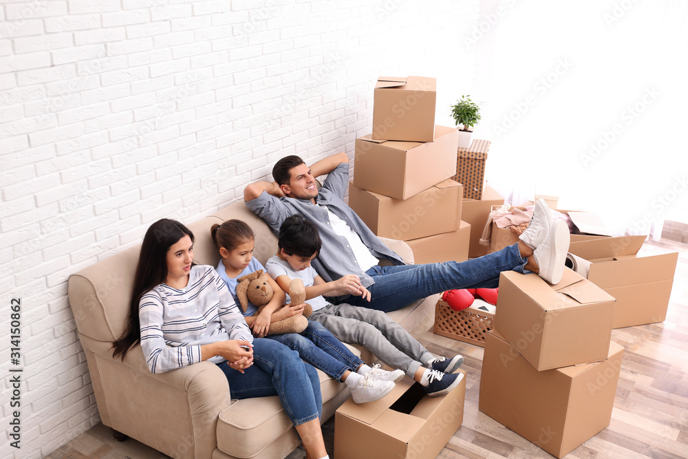 Happy family resting in room with cardboard boxes on moving day Happy family resting in room with cardboard boxes on moving day