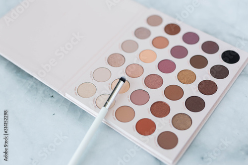 Neutral eyeshadow palette with brushes on marble background