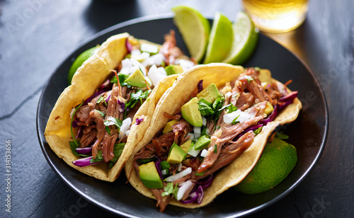 plate of mexican carnita tacos with beer in background photo