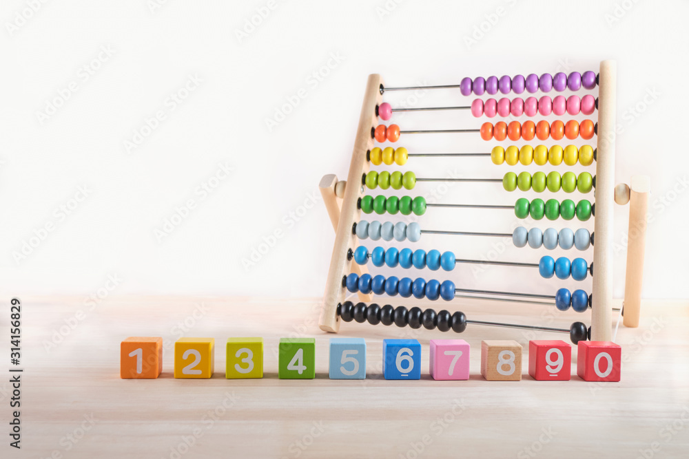 Bright colored wooden bricks with numbers and abacus toy with copy space, Numeral cubes with numbers 1, 2, 3, 4, 5, 6, 7, 8, 9 and 0 & colorful abacus, Child development, early math skills concept Bright colored wooden bricks with numbers and abacus toy with copy space, Numeral cubes with numbers 1, 2, 3, 4, 5, 6, 7, 8, 9 and 0 & colorful abacus, Child development, early math skills concept