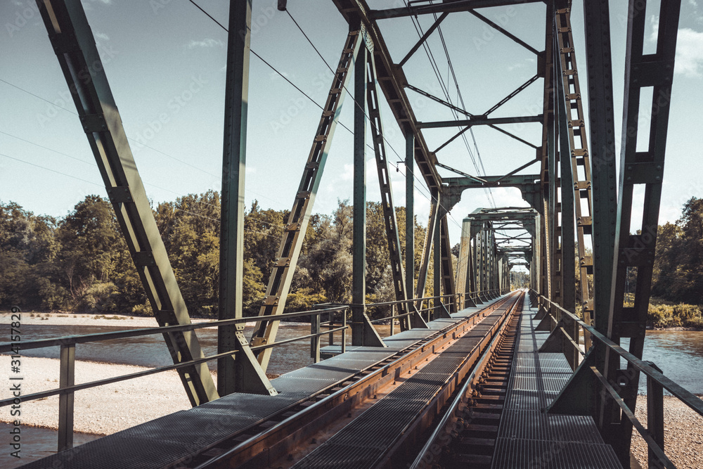 Railway bridge crossing river with trees in the background Railway bridge crossing river with trees in the background