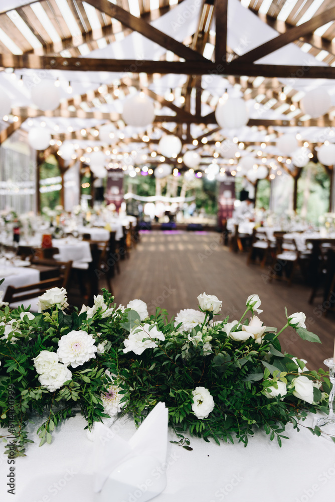 Modern wedding venue decorated with flowers and lights for a stylish boho wedding, vertical