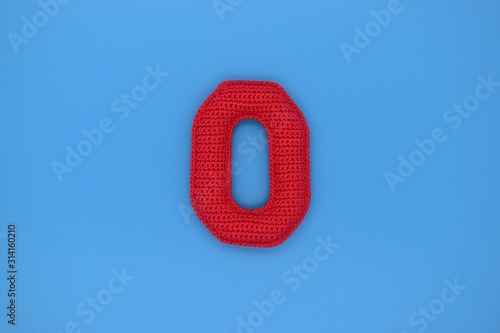 Number 0 is knitted from yarn on a blue background.