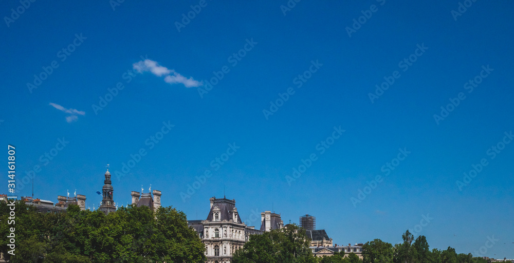 Parisian architecture and trees under blue sky, in central Paris, France