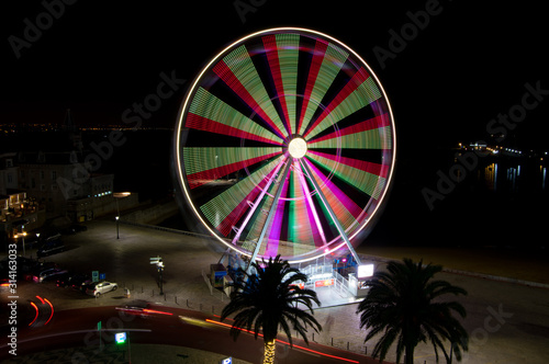 A night image of a 32 meter high Ferris wheel with varying illumination.