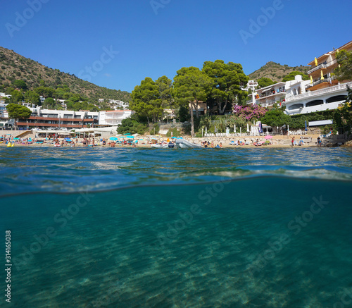 Mediterranean sea urban beach in summer in Spain on the Costa Brava with sand underwater, split view over and under water surface, Catalonia, Roses, Canyelles Petites