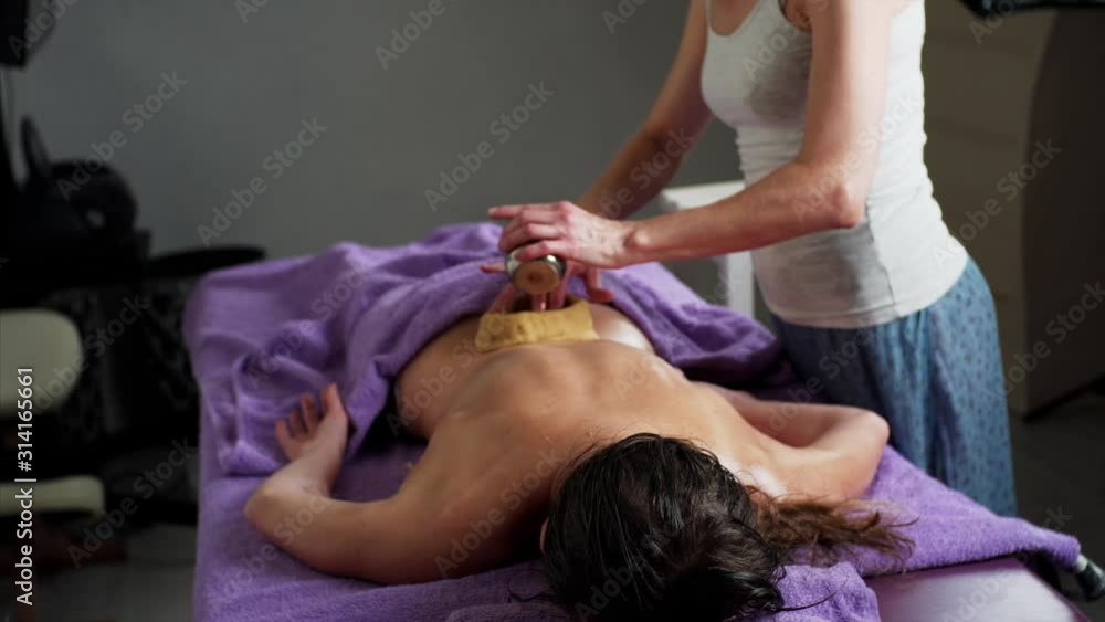 Woman is getting back ayurveda spa treatment during which masseuse is pouring warm oil into dough on woman's back. Spa salon Woman is getting back ayurveda spa treatment during which masseuse is pouring warm oil into dough on woman's back. Spa salon