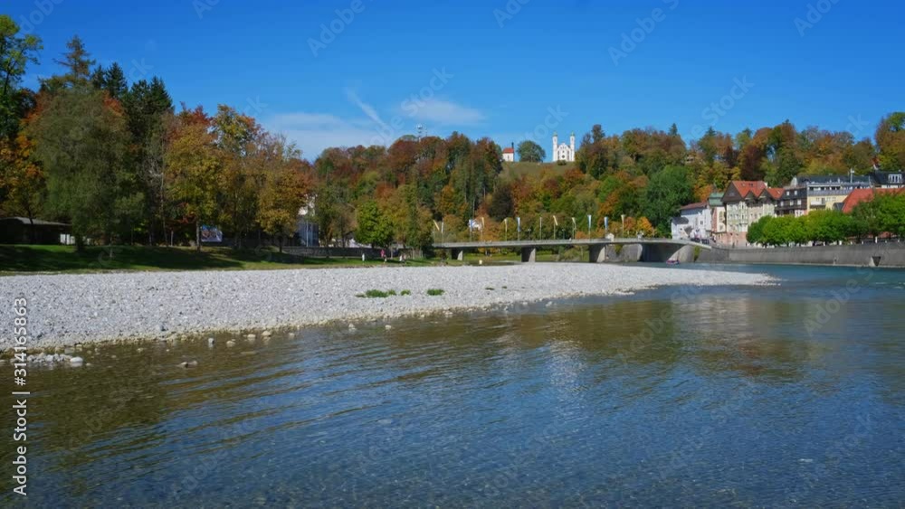 Golden autumn in famous tourist landmark medieval town Bad Tolz. View of Isar river, trees, downtown and church. Bad Toelz, Bavaria, Germany. Horizontal panning Golden autumn in famous tourist landmark medieval town Bad Tolz. View of Isar river, trees, downtown and church. Bad Toelz, Bavaria, Germany. Horizontal panning