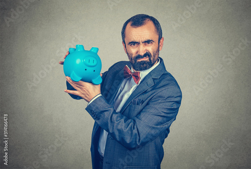 man holding overturned piggy bank, showing its emptiness photo