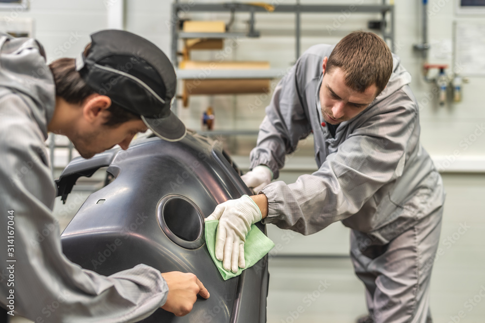 An employee of the paint shop of the automobile plant conducts training on the preparation of bumpers for painting An employee of the paint shop of the automobile plant conducts training on the preparation of bumpers for painting