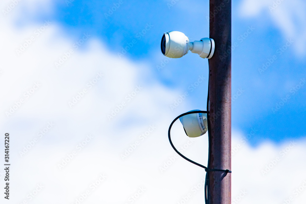 Fototapeta premium Close up components of a cell site tower. Telecommunications electronic infrastructure equipment is seen attached to a metal pole against white clouds