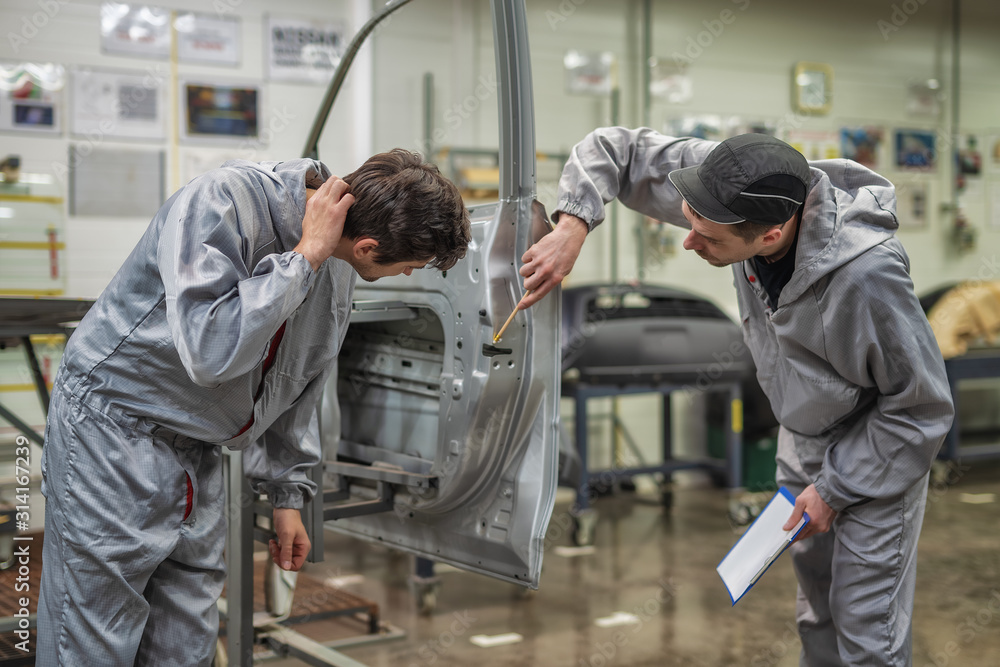 An employee of the quality Department of the car body paint shop checks the quality and indicates a defect.