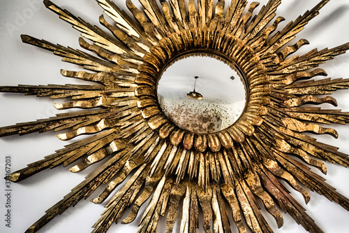 sunburst mirror on white wall showing reflection of ceiling light