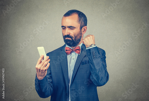 man looking at his phone and clenching his fist to the cellphone