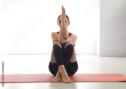 Woman practicing eagle asana in yoga studio. Garudasana pose