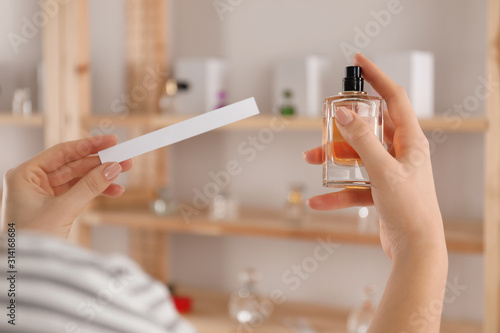 Woman with bottle of perfume and blotter indoors, closeup