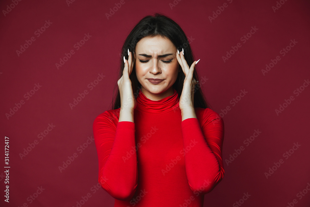 Beautiful brunette caucasian girl dressed in red pullover with painful headache on the pink background