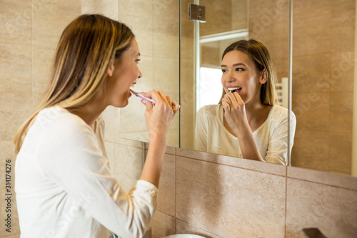 Beauty young woman cleaning teeth in bathroom