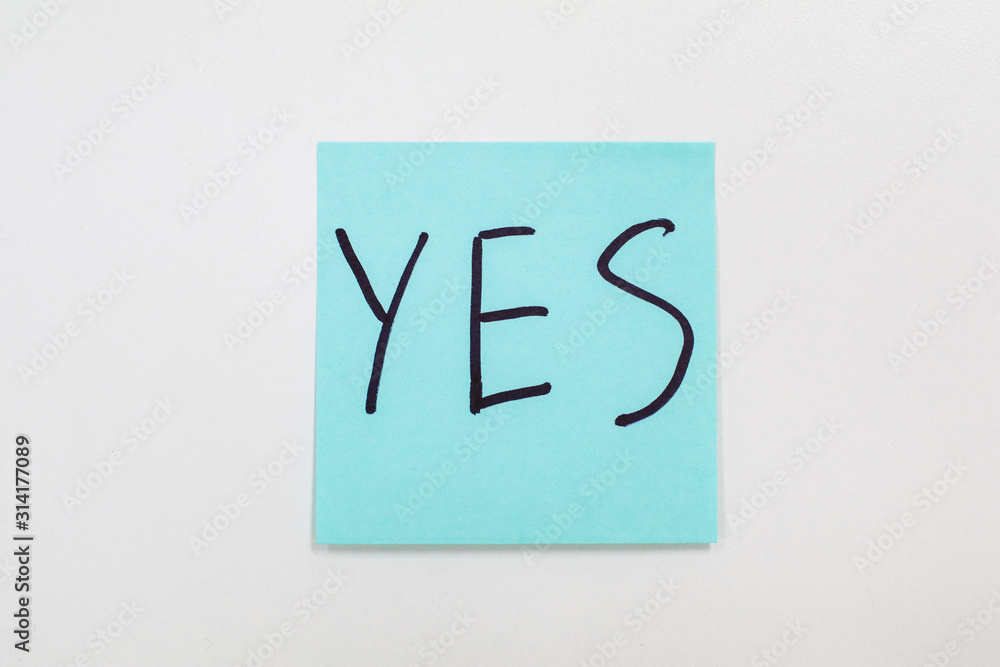 Writing on colorful sticky note Blue sticky note isolated on a white background with the word Yes Agreement and compliance concept Writing on colorful sticky note Blue sticky note isolated on a white background with the word Yes Agreement and compliance concept