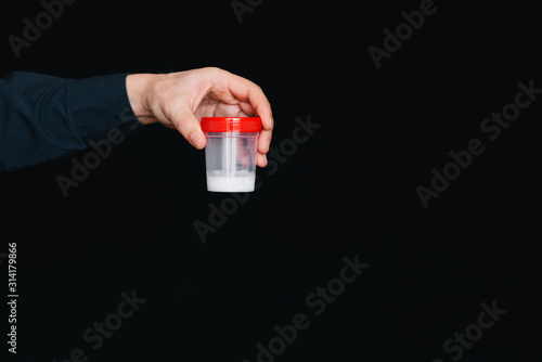 container with sperm in the hand of a male donor