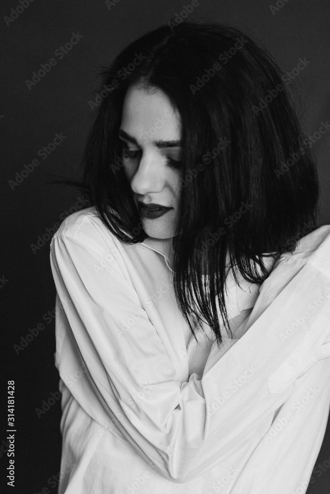 black and white portrait of beautiful young sad brunette girl in white shirt