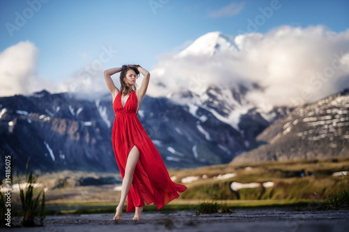 girl in a long red dress on a background of majestic mountains.