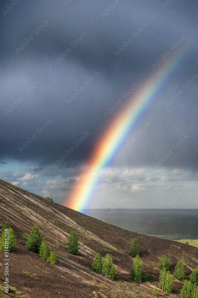 Rainbow in the mountains against a dramatic stormy sky and clouds