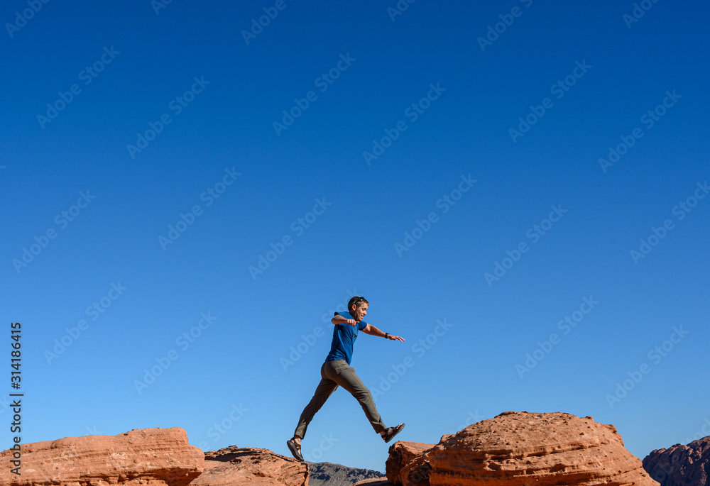 Man Jumps Between Sandstone Rocks