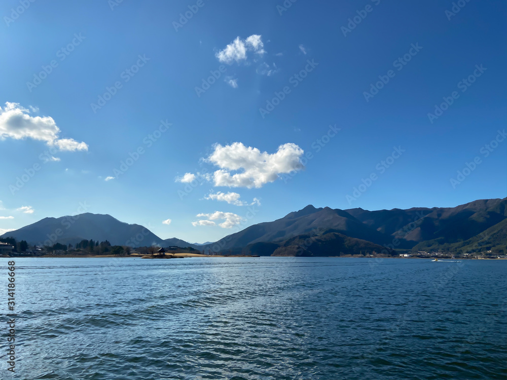Panoramic view of Kawaguchiko lake with mountain and blue sky on background with tranquil feeling of openness and fresh air under the morning sun.