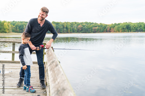Father casting a fishing pole with son at lake