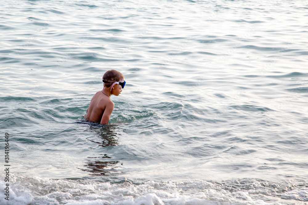 Kid swims in the sea with glasses