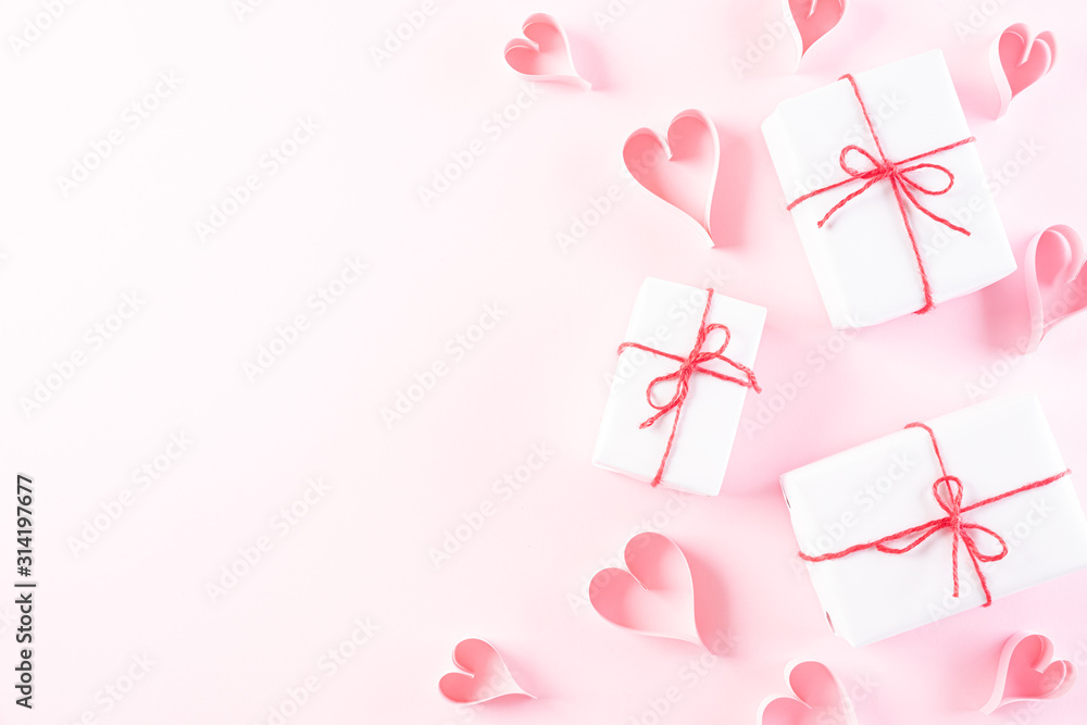Pink paper hearts with gift box on Light pink pastel paper background. Love and Valentine's day concept.