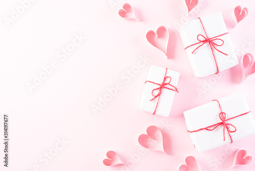 Pink paper hearts with gift box on Light pink pastel paper background. Love and Valentine's day concept.