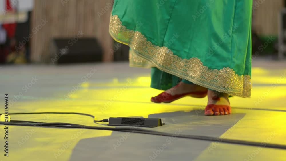 Close up shot of henna feet of an Indian classical dancer wearing Saari and anklet/ghunghroo dancing. Folk dances like Bharatnatyam, kathak etc emphasize on both hand and feet movement coordination 