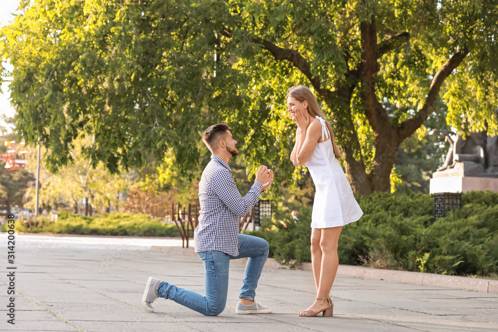 Fototapeta premium Young man proposing to his beloved outdoors