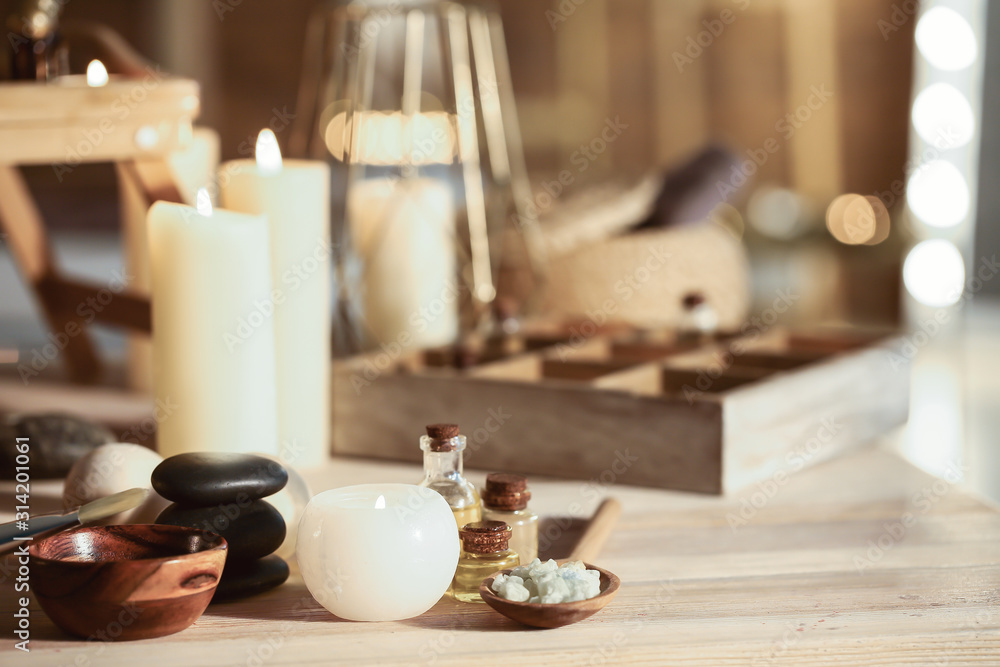 Glowing candle with spa supplies on table Glowing candle with spa supplies on table