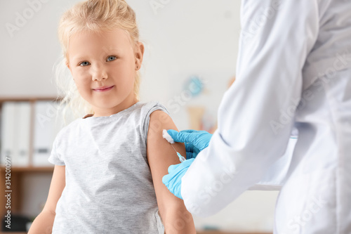 Doctor vaccinating little g...