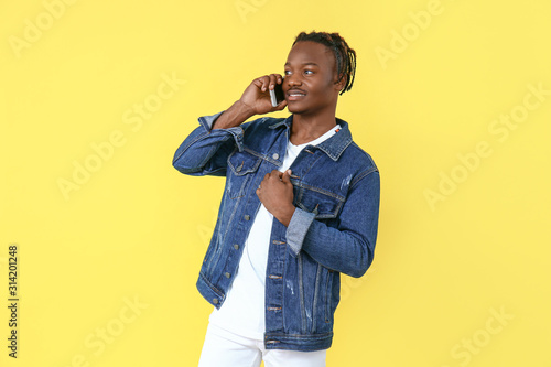 Portrait of stylish African-American man talking by mobile phone on color background © Pixel-Shot