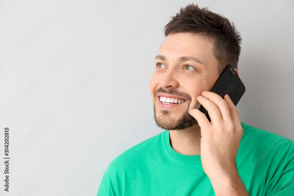 Happy man talking by mobile phone on light background Happy man talking by mobile phone on light background