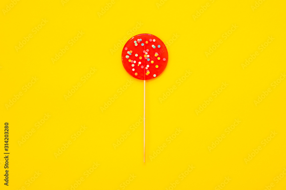 A large red Lollipop, on a yellow background. Minimal concept. A large red Lollipop, on a yellow background. Minimal concept.