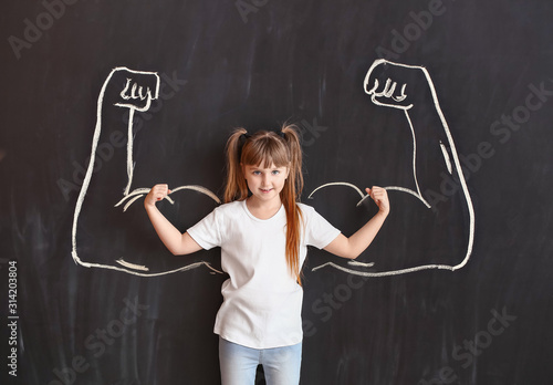Little girl near dark wall ...