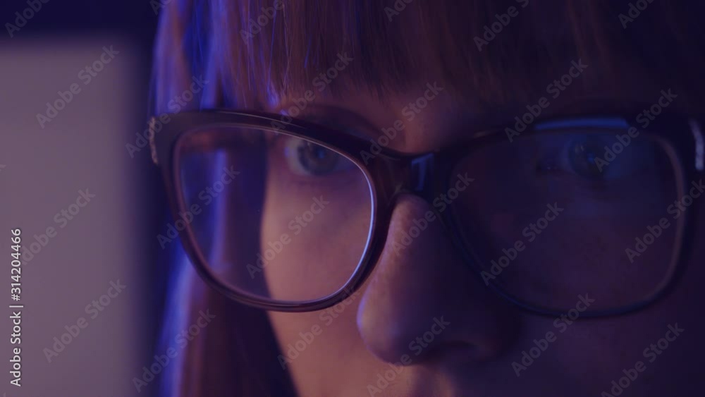 close up shot of a young tired woman, student scrolling on the phone feeling sleepy. Reflection of the smartphone screen light on the glasses close up shot of a young tired woman, student scrolling on the phone feeling sleepy. Reflection of the smartphone screen light on the glasses