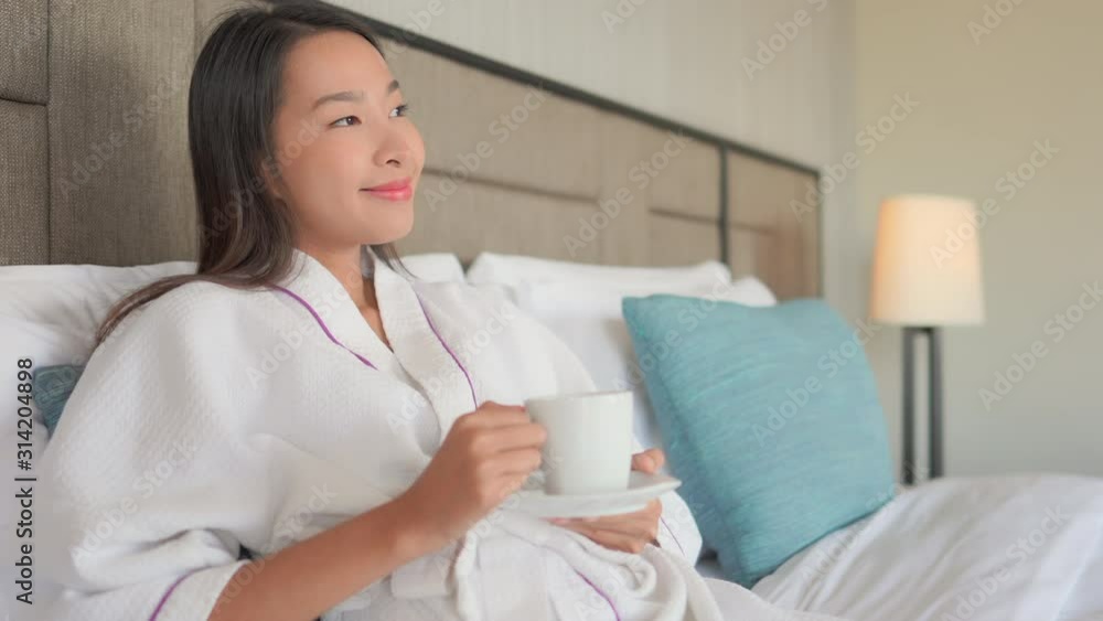 An attractive Asian woman relaxes with a cup of coffee while staying in a posh resort. An attractive Asian woman relaxes with a cup of coffee while staying in a posh resort.