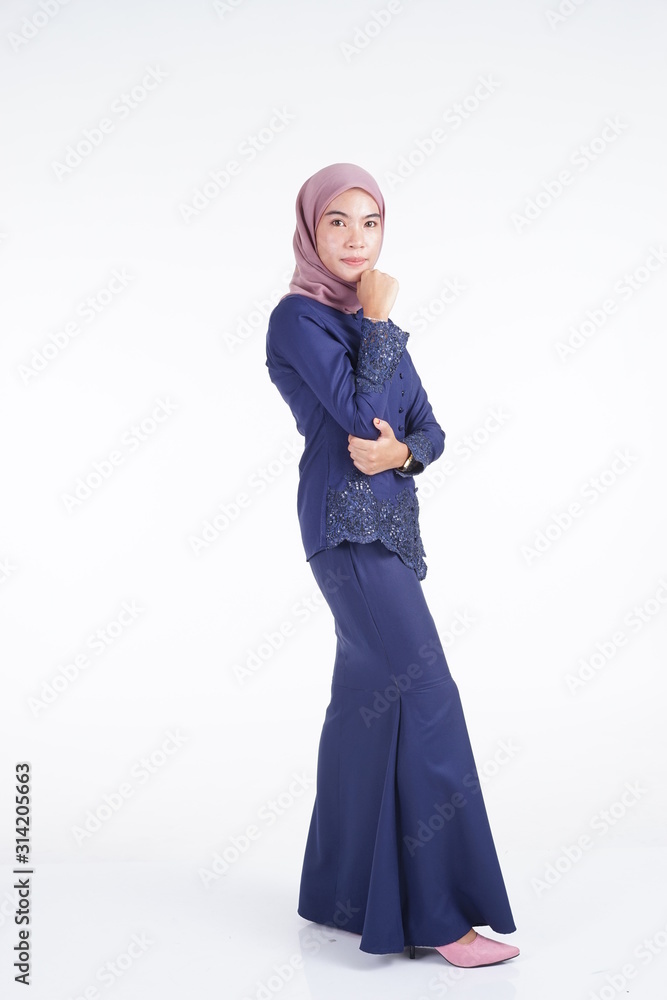 A beautiful Muslim female model wearing a dark blue modern kebaya with hijab, an Asian Muslim traditional dress isolated on white background. Eidul fitri fashion and lifestyle portrait concept. A beautiful Muslim female model wearing a dark blue modern kebaya with hijab, an Asian Muslim traditional dress isolated on white background. Eidul fitri fashion and lifestyle portrait concept.