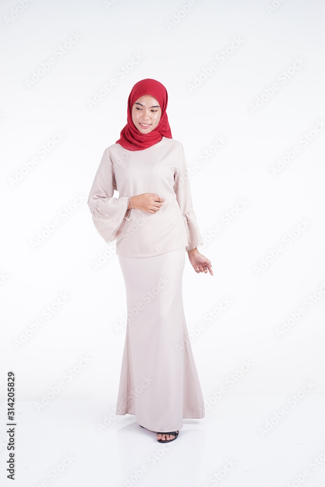 Attractive Muslim female model wearing a cream colored modern kebaya with red hijab, an Asian Muslim traditional dress isolated on white background. Eidul fitri fashion and lifestyle portrait concept.