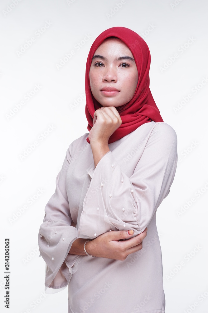 A beautiful Muslim female model in a cream colored modern kebaya with red hijab, an Asian Muslim traditional dress isolated on white background. Eidul fitri fashion and lifestyle portrait concept. A beautiful Muslim female model in a cream colored modern kebaya with red hijab, an Asian Muslim traditional dress isolated on white background. Eidul fitri fashion and lifestyle portrait concept.